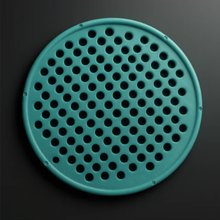 Teal circular object with holes on a black background